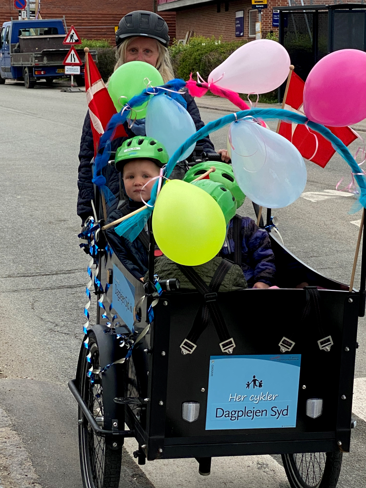 Dagplejer og børn i ladcykel med balloner