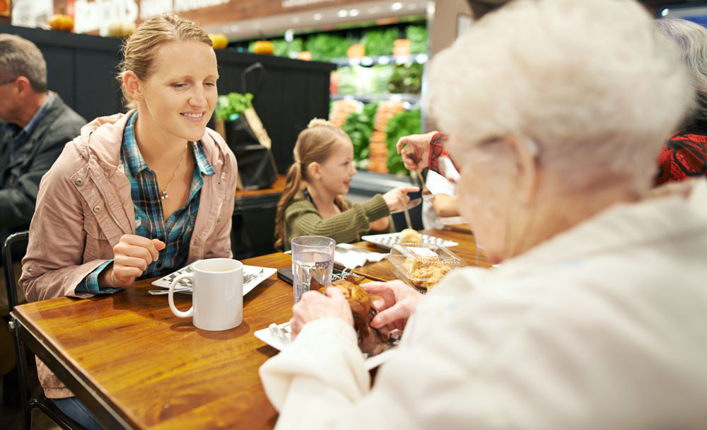 Senior kvinde og ung kvinde med barn spiser sammen